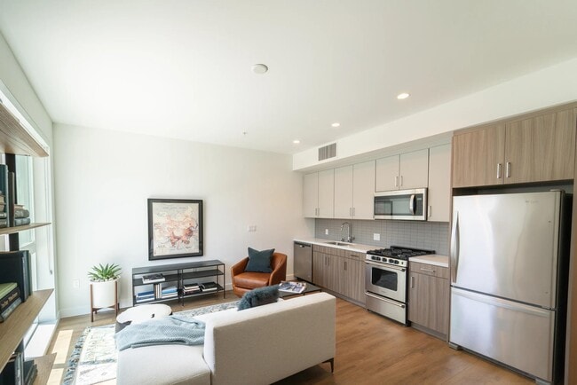 Open-concept home with dual-tone cabinetry, stainless steel appliances, and wood-style plank flooring flowing through a bright, efficient living space. - Upper Ivy