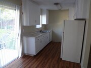 Kitchen with hardwood flooring, spacious white cabinets and sliding glass doors to porch at Villa Knolls Apartments in La Mesa, California. - Villa Knolls Apartments