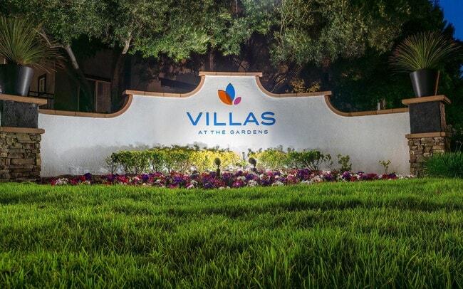 Villas at the Gardens Illuminated Entry Sign with Lush Lawn and Colorful Flowers - Villas at the Gardens Rental