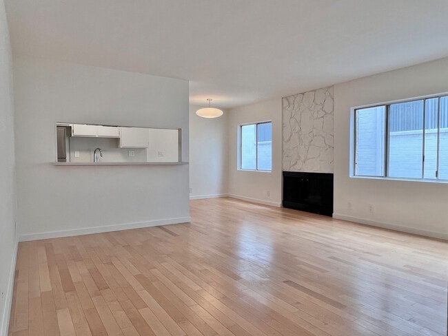 Bright, spacious living room with maple hardwood floors, fireplace, and excellent natural light. - 11639 Chenault St Unit 403