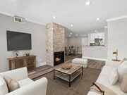 Living room with stone accented fireplace and mounted television. - Catalina Apartments