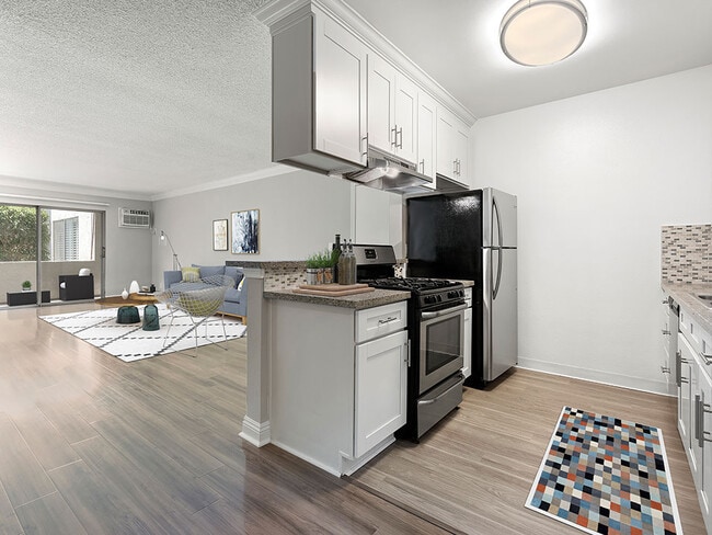 Custom tiled kitchen with view of hardwood floored living room and balcony. - Rose North