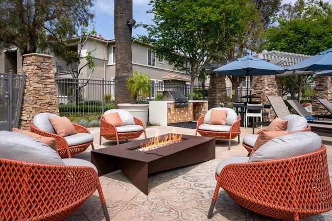 Outdoor Fire Pit Lounge with Woven Chairs and Poolside Seating Nearby - Camino Real Apartments