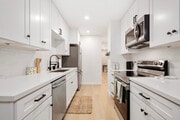 Sleek kitchen with stainless steel appliances, white cabinets, and open layout. - 1013 S Sunshine Ave Condo Unit K