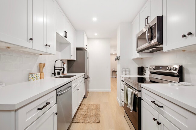 Sleek kitchen with stainless steel appliances, white cabinets, and open layout. - 1013 S Sunshine Ave Unit K