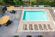 Private Pool Area with Lounge Chairs and Patio Tables with Umbrellas - Villas at the Gardens Apartments