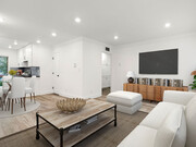 Large hardwood floored living room with view to kitchen and hallway storage. - The Glendon Building Apartments