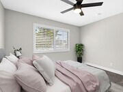 Carpeted bedroom with ceiling fan and large windows. - Woodridge Apartments