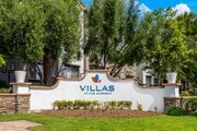Welcoming Villas at the Gardens Signage Surrounded by Trees and Flowers - Villas at the Gardens Apartments