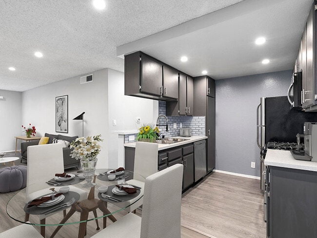 Hardwood floor dining room with view of tiled kitchen area. - Woodridge Apartments