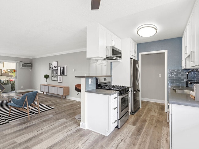 Kitchen with blue tile backsplash and view of adjacent living room. - Rose Avenue