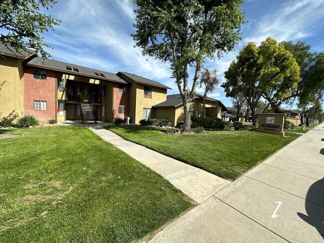 Sidewalk view of lawn and gardens at Riverdale Apartment Homes in Hemet, California. - Riverdale Apartments