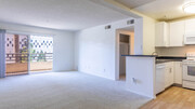 Kitchen and Carpeted Living Room with Balcony - Park West Apartments