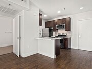Tiled kitchen with stained wood cabinets and stainless steel appliances. - Bonita Terrace Apartments