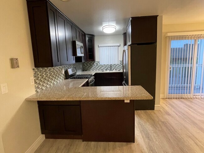 Rich chocolate cabinets, granite counters with room for bar stools. - 2411 Prospect Ave Unit 107