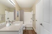 Renovated Package I bath with beige granite countertops, white cabinetry, and hard surface flooring - eaves Lake Forest Apartments