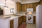 Classic Package I kitchen with white appliances, white tile countertop, oak cabinetry, and tile flooring - Avalon Thousand Oaks Plaza Apartments