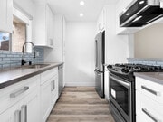 Blue tiled kitchen with stainless steel oven, fridge, dish washer, and fixtures. - 1249 South Bundy Apartments