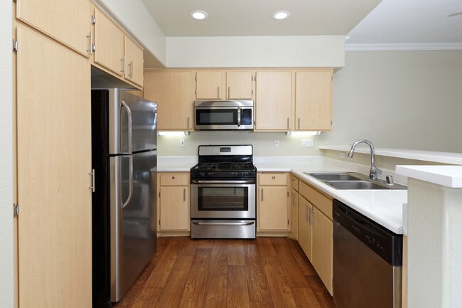 Classic Package II kitchen with stainless steel appliances, laminate countertops, oak cabinetry, and hard surface flooring - Avalon Mission Oaks