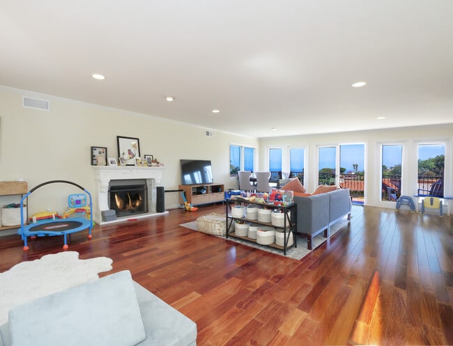 Living room with wood floors, fireplace and walls of glass to views and balcony - 345 Palos Verdes Dr W