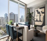 Modern apartment interior with elegant dining area, plush seating, and panoramic city views through large windows. - Ancora