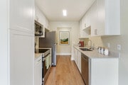Renovated Package I kitchen with beige granite countertops, white cabinetry, stainless steel appliances, and hard surface flooring - eaves Lake Forest Apartments