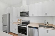 Freestanding Home kitchen with stainless steel appliances, white cabinetry, beige quartz countertops, and hard-surface flooring - eaves San Marcos Apartments