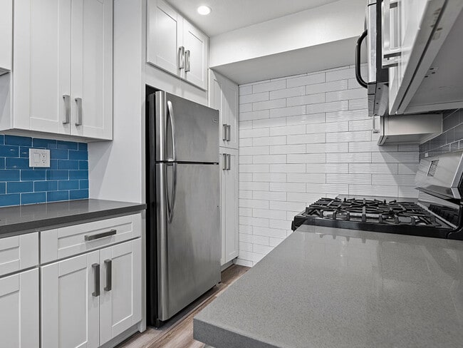 Blue tiled kitchen with stainless steel oven, fridge, and fixtures. - Hi Point Townhomes