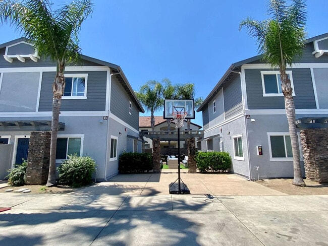 Community area with backetball hoop and sitting area in background at The Nines Townhomes in Escondido, California. - The Nines Townhomes