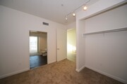 Carpeted bedroom with spacious closets and shared bathroom at 12th Street Lofts in National City, California. - 12th Street Lofts