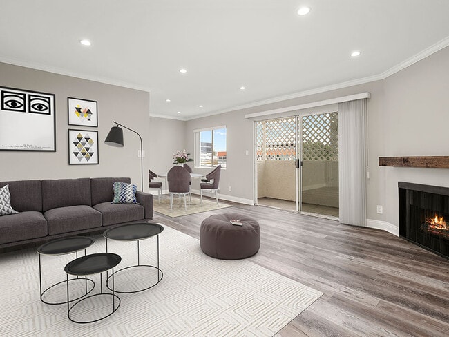 Living room with hardwood floors and view of balcony. - Vinton Apartments