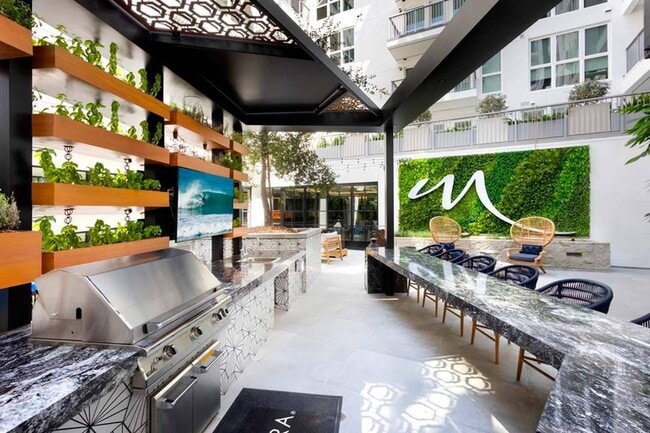 One of two lushly-landscaped courtyards with outdoor kitchen, bar seating, and TV - Modera San Diego