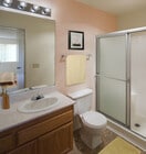 Classic Package bath with oak cabinetry, beige speckled laminate countertops, and tile flooring - eaves La Mesa Apartments