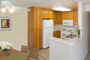 Classic Package kitchen with oak cabinetry, beige speckled laminate countertops, tile flooring, and white appliances - eaves La Mesa Apartments
