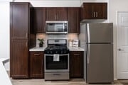 Apartment Kitchen with Dark Cabinetry, Full Appliance Suite, and Subway Tile Backsplash - Camino Real Apartments