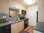Classic Package I kitchen with black appliances, maple cabinetry, dark grey laminate countertops, and hard surface flooring - eaves South Coast