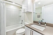 Renovated Package II bath with light grey quartz countertop, white shaker cabinetry, and hard surface flooring - eaves Thousand Oaks Apartments