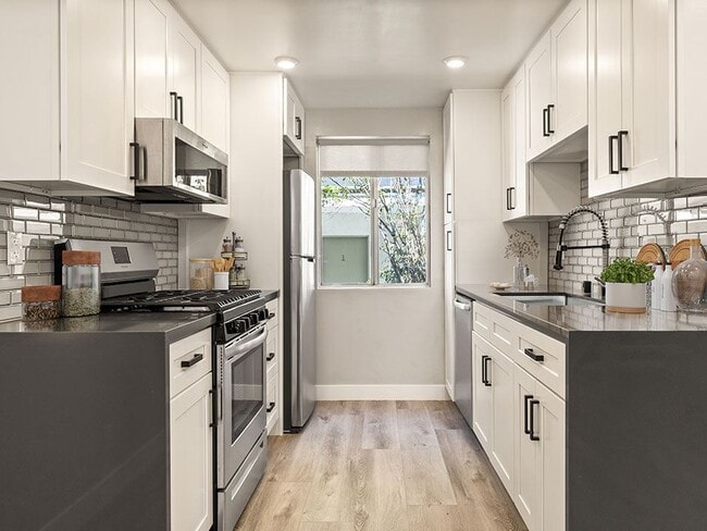 Tiled kitchen with stainless steel microwave, oven, fridge, and fixtures. - The Glendon Building