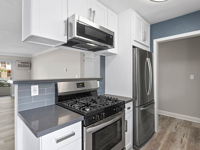 Kitchen with blue tile backsplash and stainless steel Stove, Oven, and fixtures. - Rose Avenue