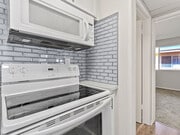 White tiled kitchen with stainless steel oven and microwave. - Riverbridge Apartments