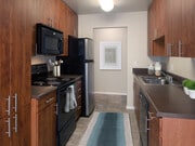 Classic Package II kitchen with dark laminate countertops, cherry cabinetry, black appliances, and hard surface flooring - eaves Lake Forest Apartments