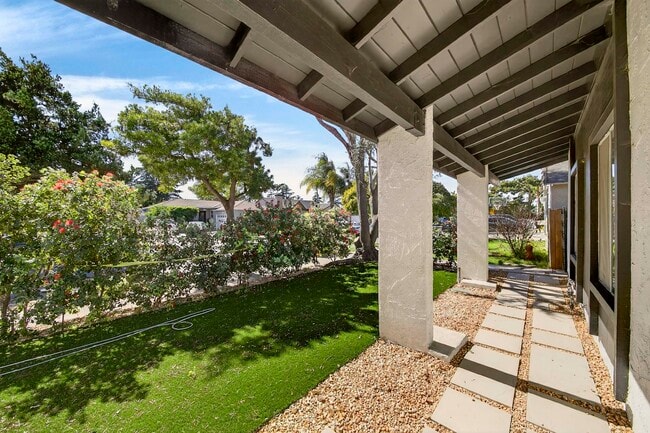 The exposed beam overhang and stucco columns frame a manicured private front lawn - 5214 Dawes Ave