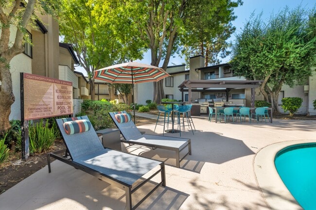 Chatsworth Pointe's spacious pool deck with chairs and umbrellas. - Chatsworth Pointe Apartment Homes