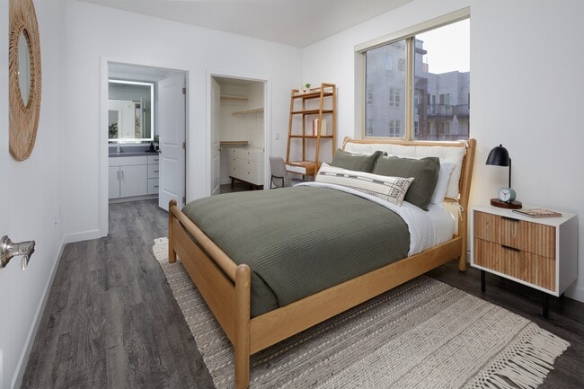 model bedroom with a bed and a large window - Esperanza at Duarte Station
