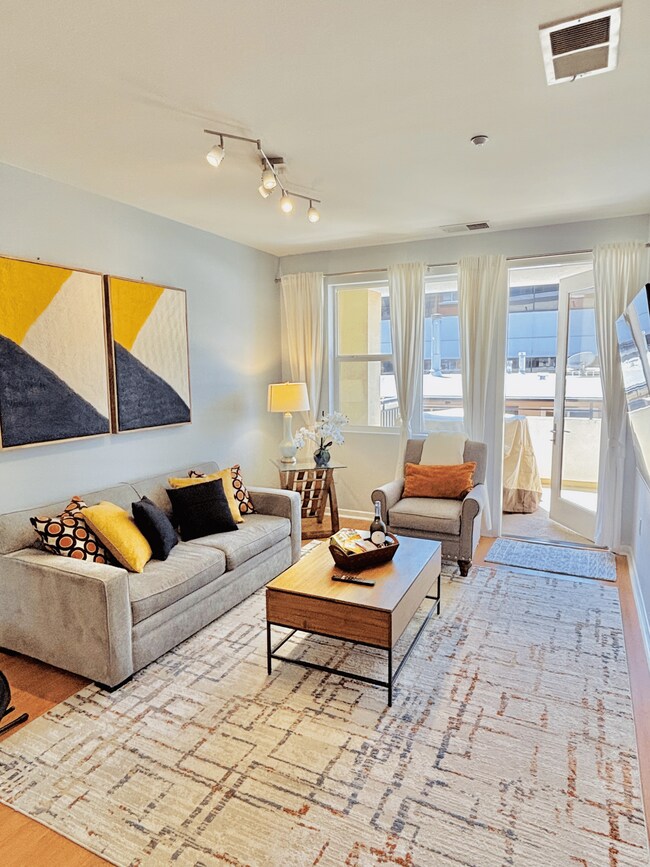 Bright, open living space with 65" 4K Smart TV, sleeper sofa & natural light. - 3687 4th Ave Unit 203