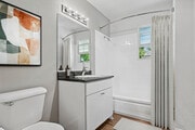 Bath with white cabinetry, black laminate countertops, and hard surface flooring - AVA Newport Apartments