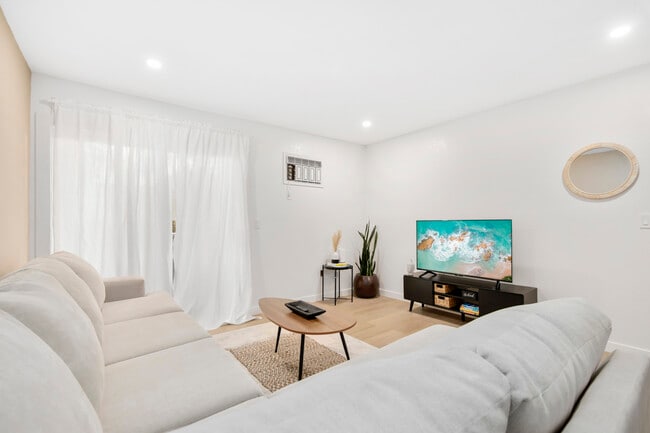 Bright living room with natural light, cozy seating, and smart TV – perfect for relaxing. - 1013 S Sunshine Ave Condo Unit K