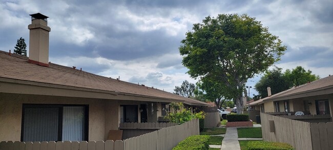 Mature trees and gardens along walkways at Las Casitas Apartments in Riverside, California. - Las Casitas Apartments
