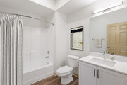 Renovated Package I bath with white speckled quartz countertop, white cabinetry, and hard surface flooring - Avalon Thousand Oaks Plaza Apartments